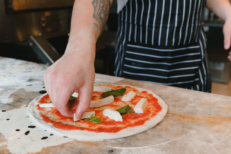 Green lantern pizza handcrafted pizza being prepared in Rochester Hills kitchen
